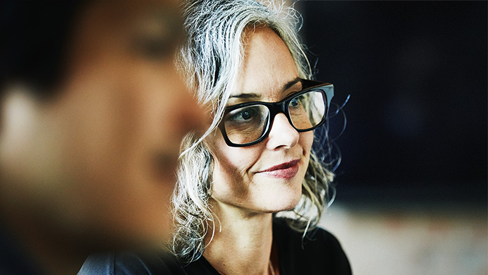 A seated person with glasses listening and smiling