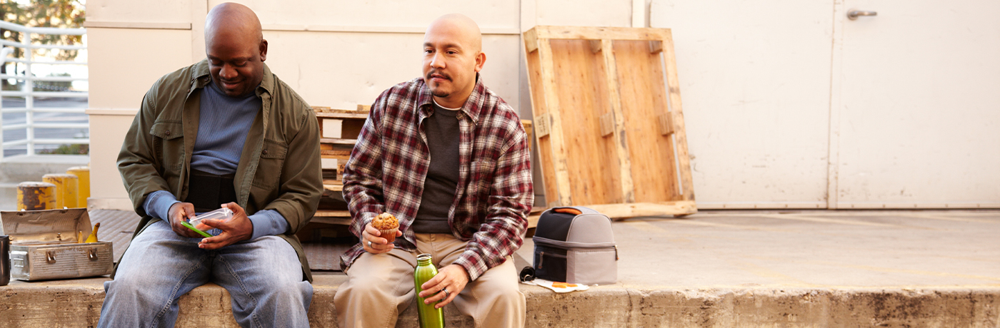 Two workers sitting on a loading dock having lunch
