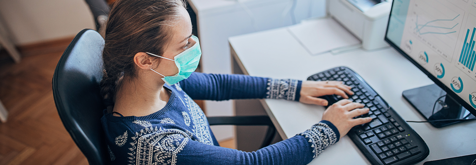 Woman working at her desk while wearing a disposable mask
