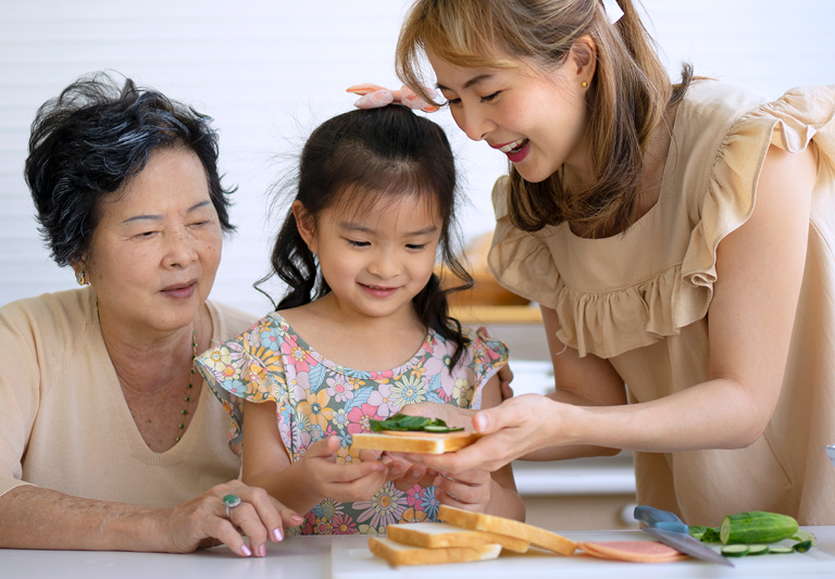 A smiling caregiver with their elderly parent and young child