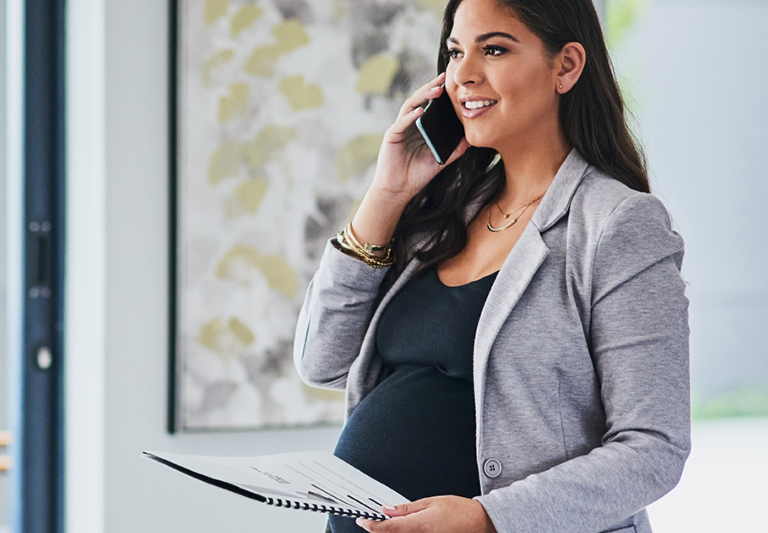pregnant person holding a notebook and a phone